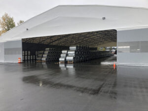 Gable end view of a 38m wide low profile structure. There is a wide opening in the end and inside are steel coils stacked in long rows. Overall fabric structure is 38m x 60m